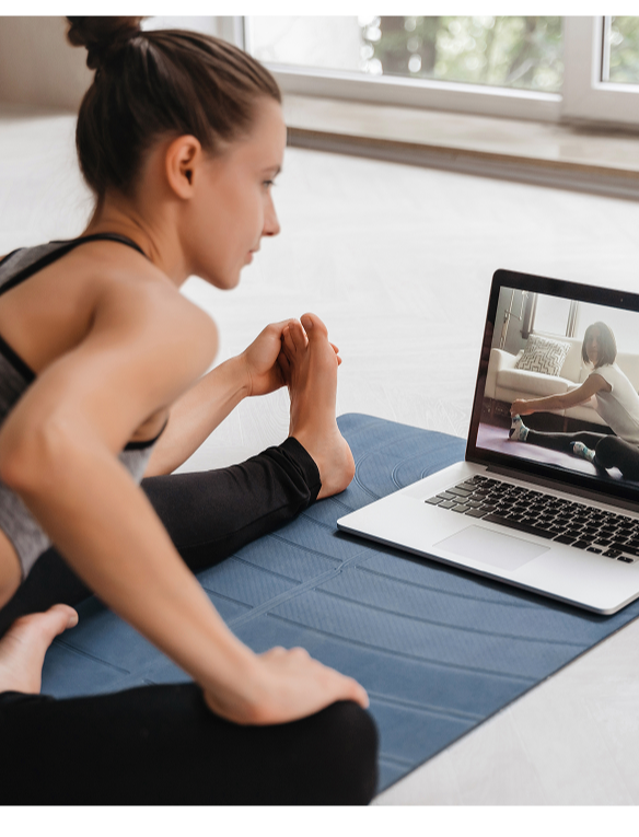 Woman doing an online Pilates workout at home using a laptop