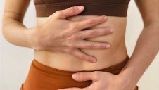 Woman gently holding her postpartum belly during early recovery