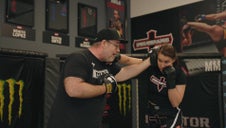 Coach K holding mitts for jab defense drill with female fighter