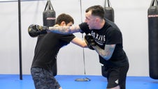 Fighting throwing a cross to the body as coach catches it with a mitt and throws a cross