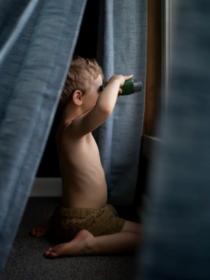Child peeking through curtains with binoculars, representing discovery and the editing process in photography.