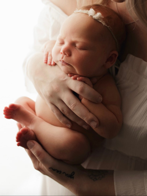 Newborn baby cradled in mother’s arms, symbolizing newborn photography and gentle posing.