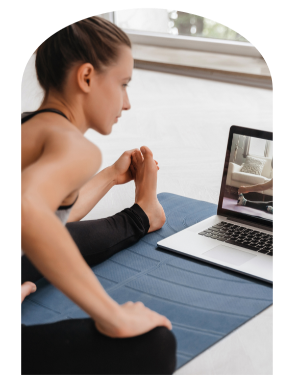 Woman doing an online Pilates workout at home using a laptop