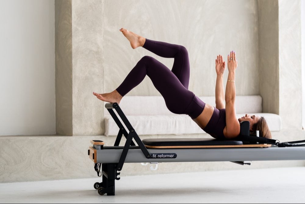 Maghan on the Reformer, hips lifted with one leg extended