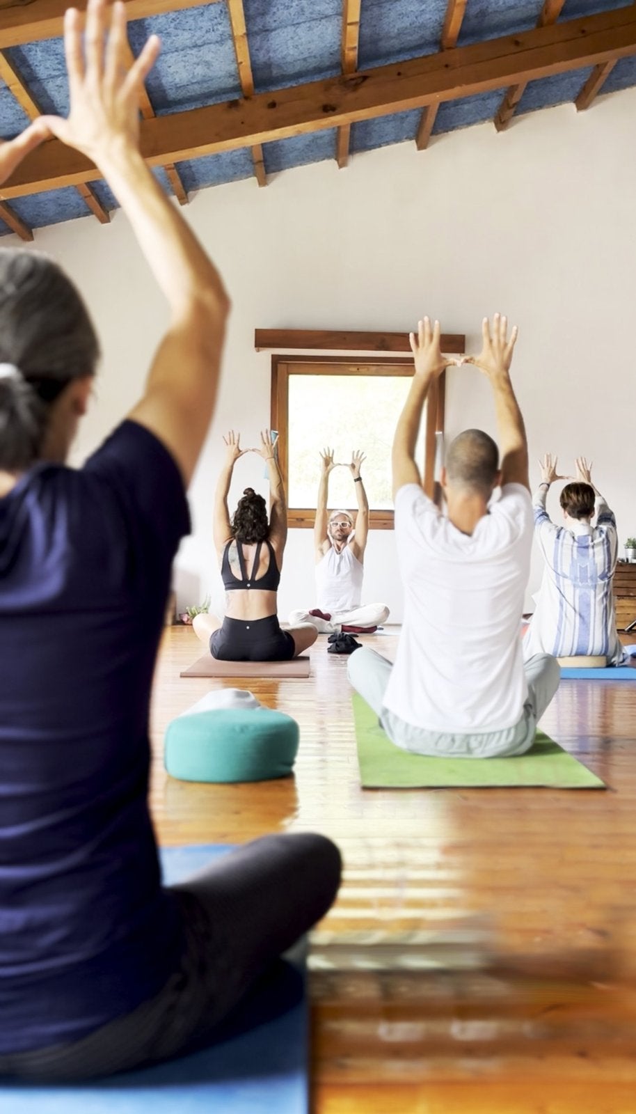 Andrew leading a seated class with arms raised, the group following him