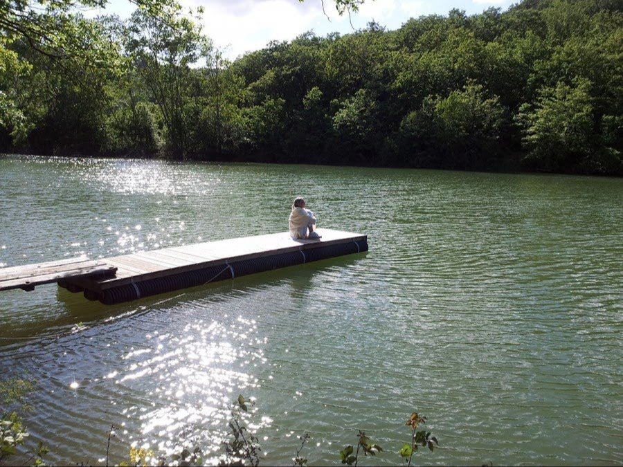 A guest sitting on a wooden pontoon on the lake
