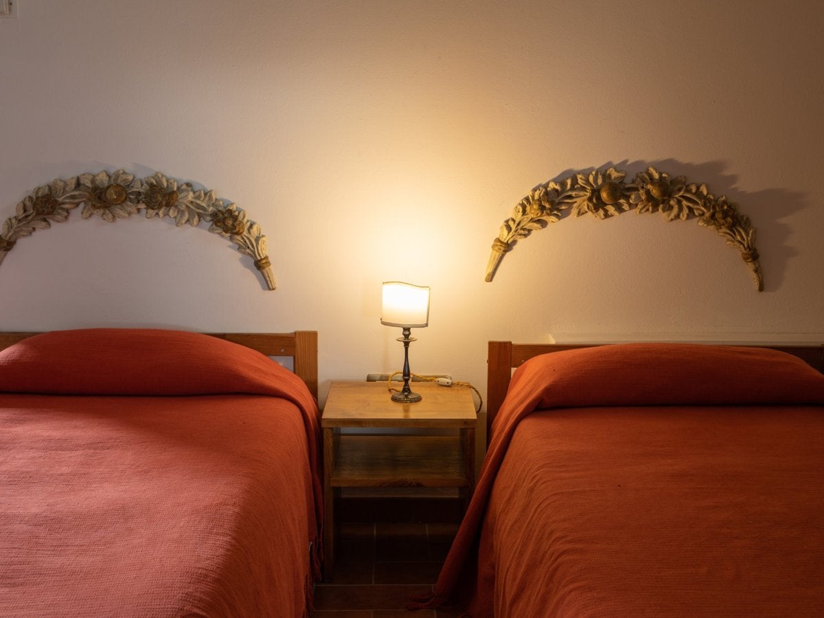 A double room with two single beds and a bedside lamp