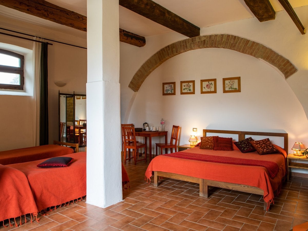 The shared room for 4, with a double bed under a brick arch and two single beds