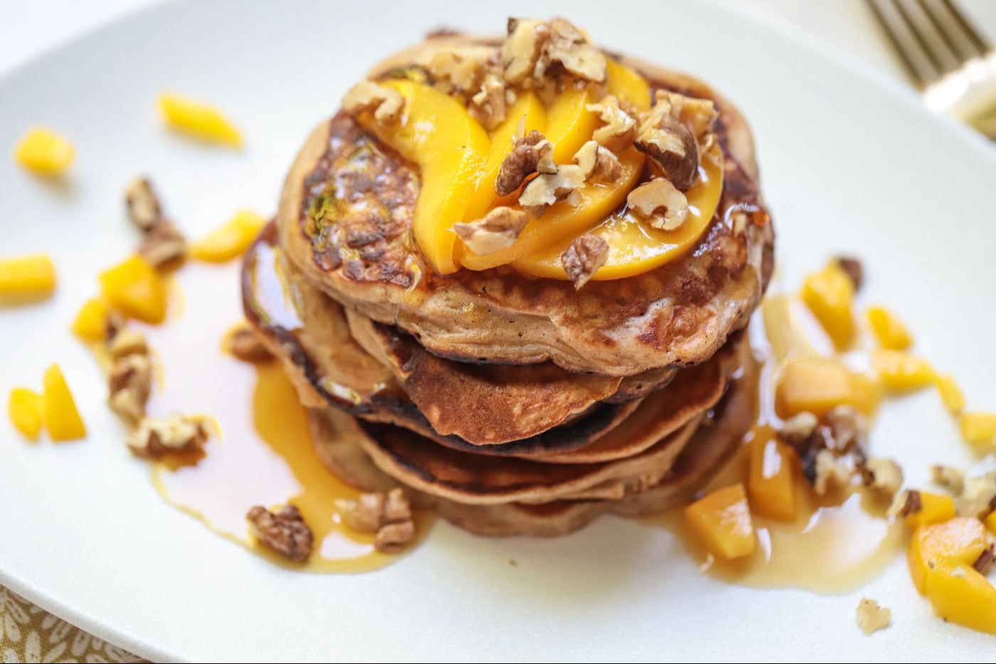 Peach pancakes stacked on a plate