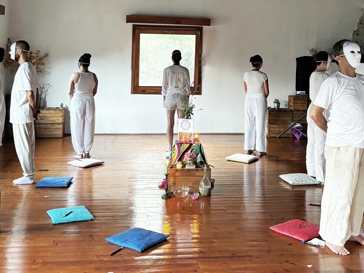 Retreat participants dressed in white in a wooden-beamed practice hall in Italy