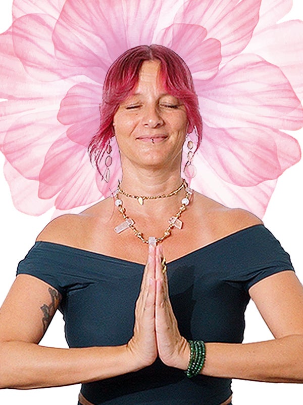 Clelia, eyes closed, hands in prayer, in front of a large pink flower