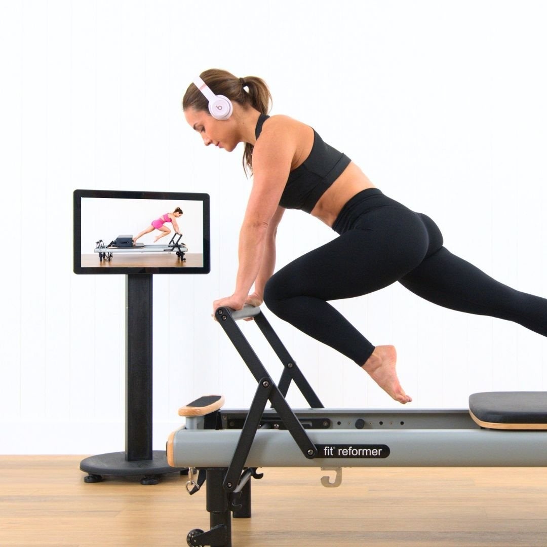Following a class on the StudioConnect screen beside a fit reformer