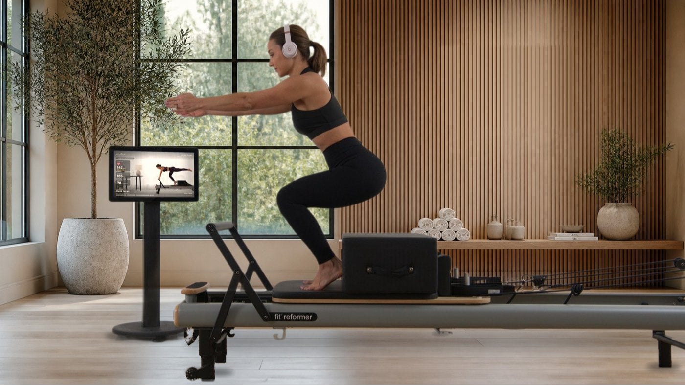 Maghan training on a fit reformer with the StudioConnect kiosk in a boutique Pilates studio